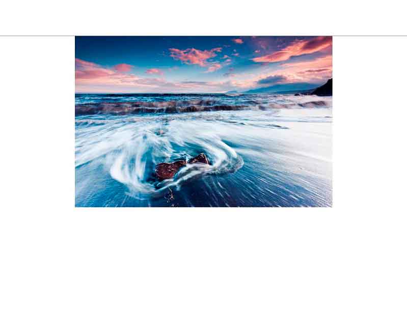 Dynamische Wellen brechen sich an der Küste bei Sonnenuntergang mit beeindruckenden Farben am Himmel.