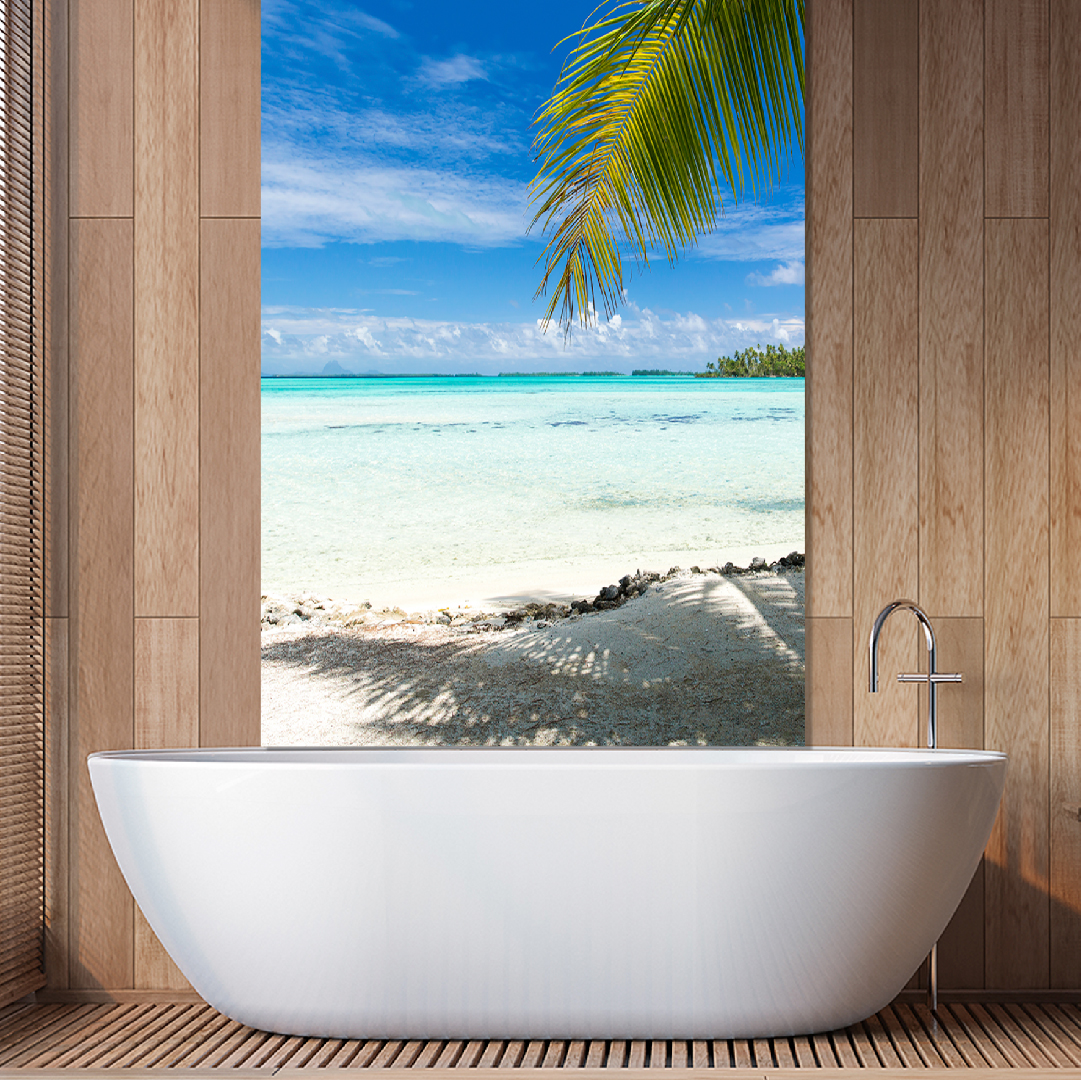 Moderne Badewanne vor Strandpanorama mit Palmen Elegante weiße Badewanne in einem Holzraum mit Blick auf einen sonnigen Strand und türkisfarbenes Meer durch ein großes Fenster, dekoriert mit Palmenblättern.